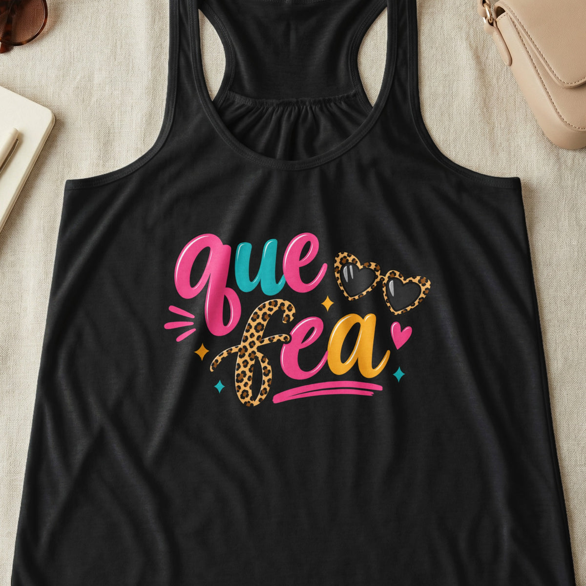 Black tank top with colorful "Que Fea" graphic and leopard print hearts.
