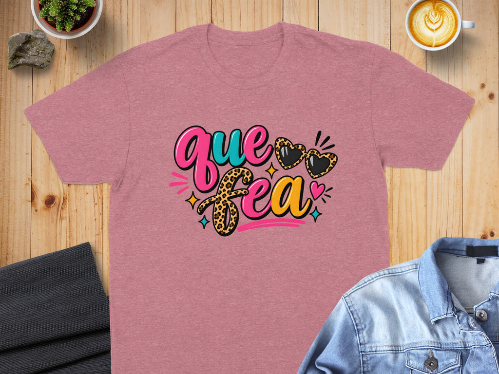 Pink t-shirt with "Que Fea" text and leopard print heart sunglasses.