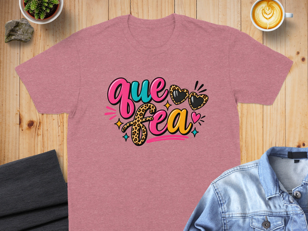 Pink t-shirt with "Que Fea" text and leopard print heart sunglasses.