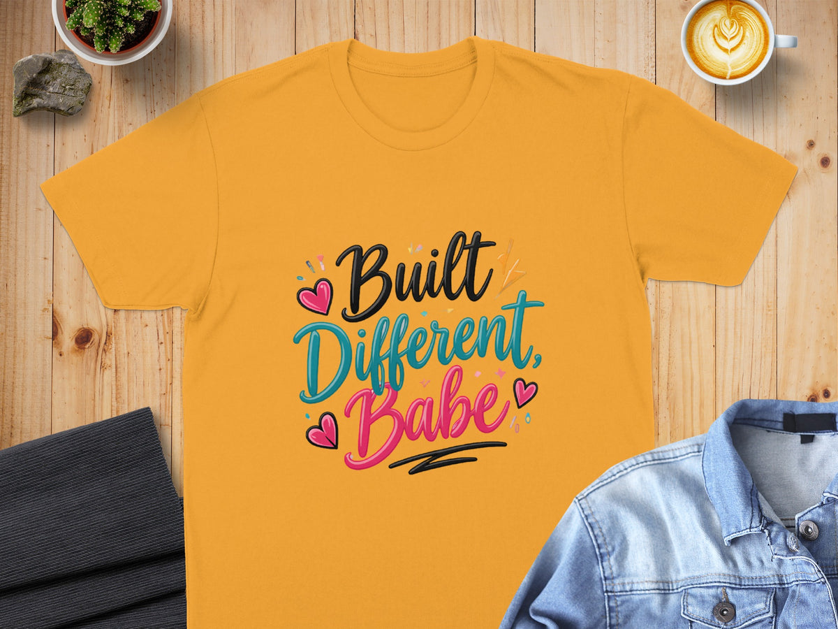 Yellow t-shirt with "Built Different, Babe" text and pink and teal hearts.